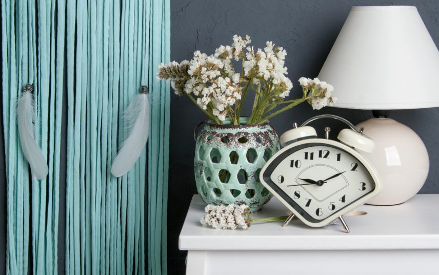 Idee für Schlafzimmerdekoration – Beispiel mit dekorierter Nachtkonsole – Retro Glockenwecker  Vase mit Blumen & Nachttischlampe – Blauer Wandbehang mit Federn