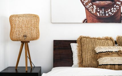 Afrikanische Schlafzimmerdekoration Idee – Beispiel mit Nachttischlampe aus Rattan auf dem Holznac...