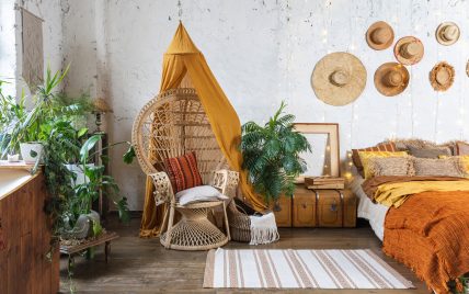 Gestaltungsidee für ein Schlafzimmer im coolen Hippie Style mit Truhe als Ablage & großen Korbstuh...