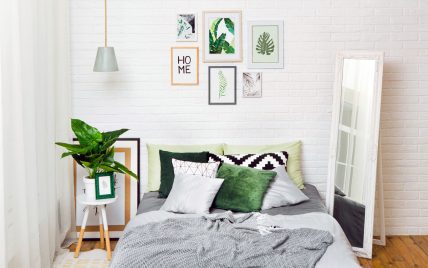 Gemütliches Schlafzimmer mit Wanddekoration als Wohnidee – Bett mit vielen Kissen- weißer Stands...