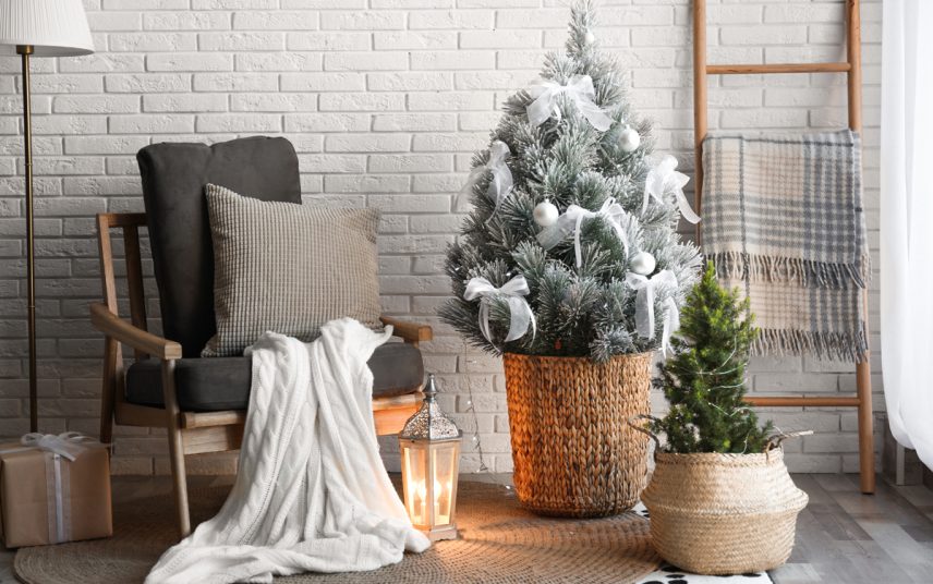 Wohnidee – Hyggeliger Sitzbereich mit Dekoleiter & Weihnachtsdekoration – Retrosessel mit Kissen & Decke – Weiß angesprühter Weihnachtsbaum im Korbgefäß
