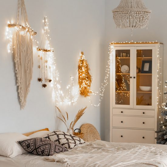 Stilvoll dekoriertes Schlafzimmer im Landhausstil mit Weihnachtsdeko - Wohnidee mit Lichterkette & Wandteppich Makramee als Deko - Bett mit Kissen & Decken
