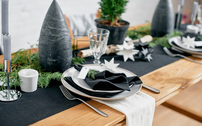 Beispiel mit einfacher weihnachtlicher Tischdeko – Idee mit dunklen Tischläufer  großer Kerze  Kerzenständer & Tannenzweigen auf dem Esstisch aus Holz