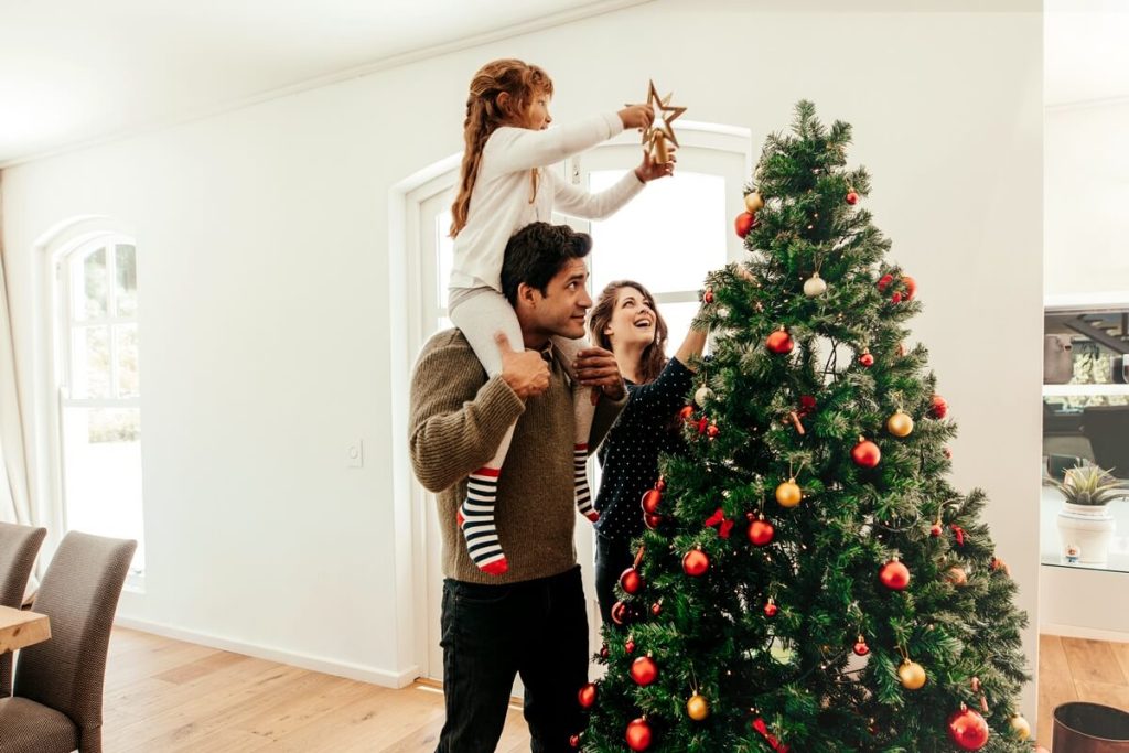 Familie setzt Weihnachtsstern auf die Spitze des Weihnachtsbaums