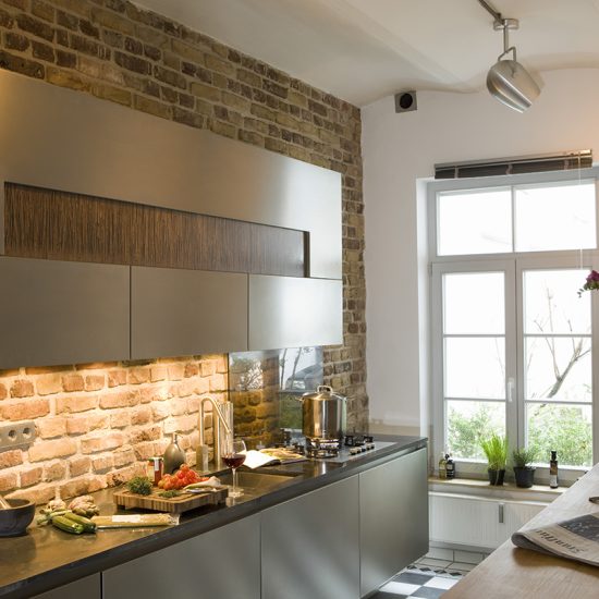Einrichtungidee für die Küche - Designküche mit großen Wandschrank an einer rustikalen Wand - Schrankbeleuchtung & Deckenlampe - Tresentisch mit Vase & Blume