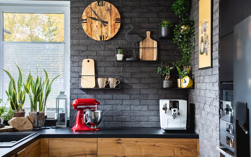 Wohnidee – Rustikale Küche mit dunkler Steinwand & Wandgestaltung – schwarze Wandregale aus Metall – Küchenuhr aus Holz & Küchendekoration