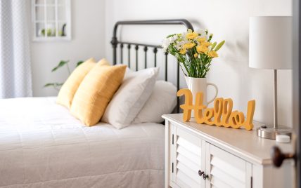 Schlafzimmer mit Frühlingsdekoration – Blumenstrauß neben dem schwarzen Metallbett – Nachtschr...