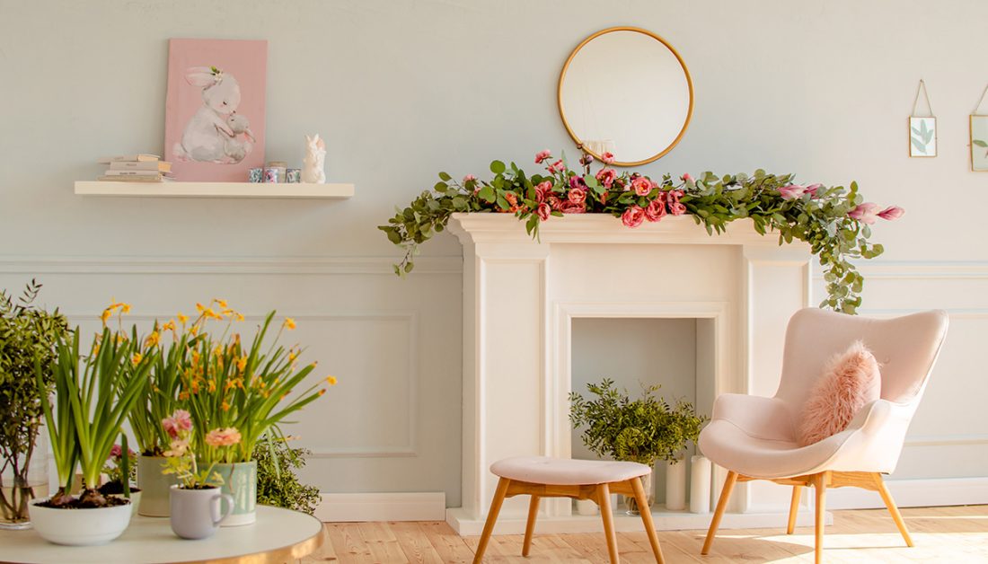 Stilvoll eingerichtete Wohnung für den Frühling - Blumengirlande auf der Kaminkonsole - Moderner Sessel mit Hocker - Wandregal mit Bild & Osterdeko
