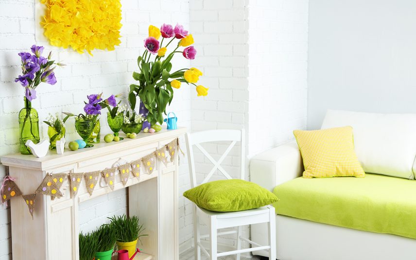 Frühlingsdekoration an & auf der Kaminkonsole – Vasen mit Frühlingsblumen – Weißer Stuhl mit grünem Kissen – Ostereier & Osterfiguren