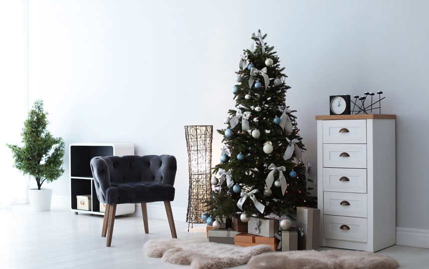 Moderner Sitzbereich mit stilvoll geschmückten Weihnachtsbaum & Dekoration – Retrosessel  weiße Kommode & Kunstfelle