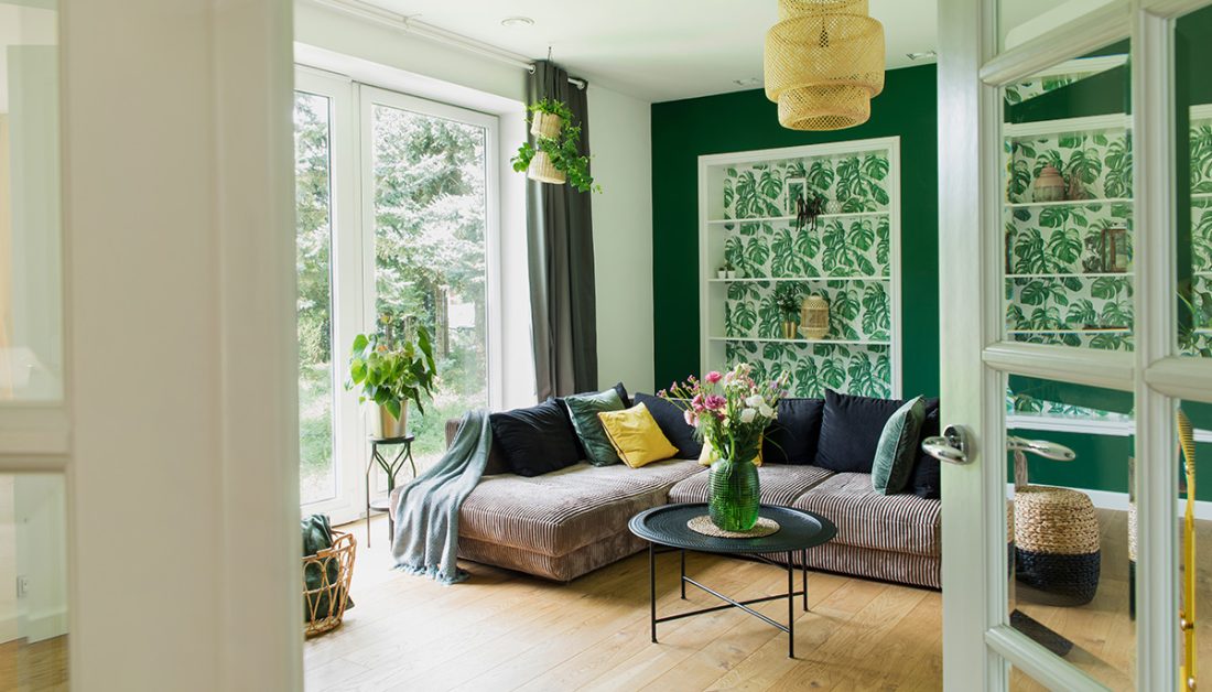 Wohnzimmer-Gestaltung im grünen Farbton mit braunem Sofa & Sommerdekoration