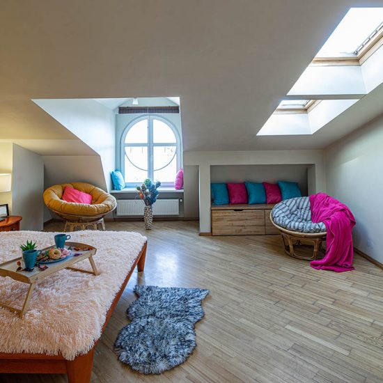 Großes Gästezimmer im Dach mit Doppelbett und Korbstühlen  bunte Akzente mit farbigen Kissen