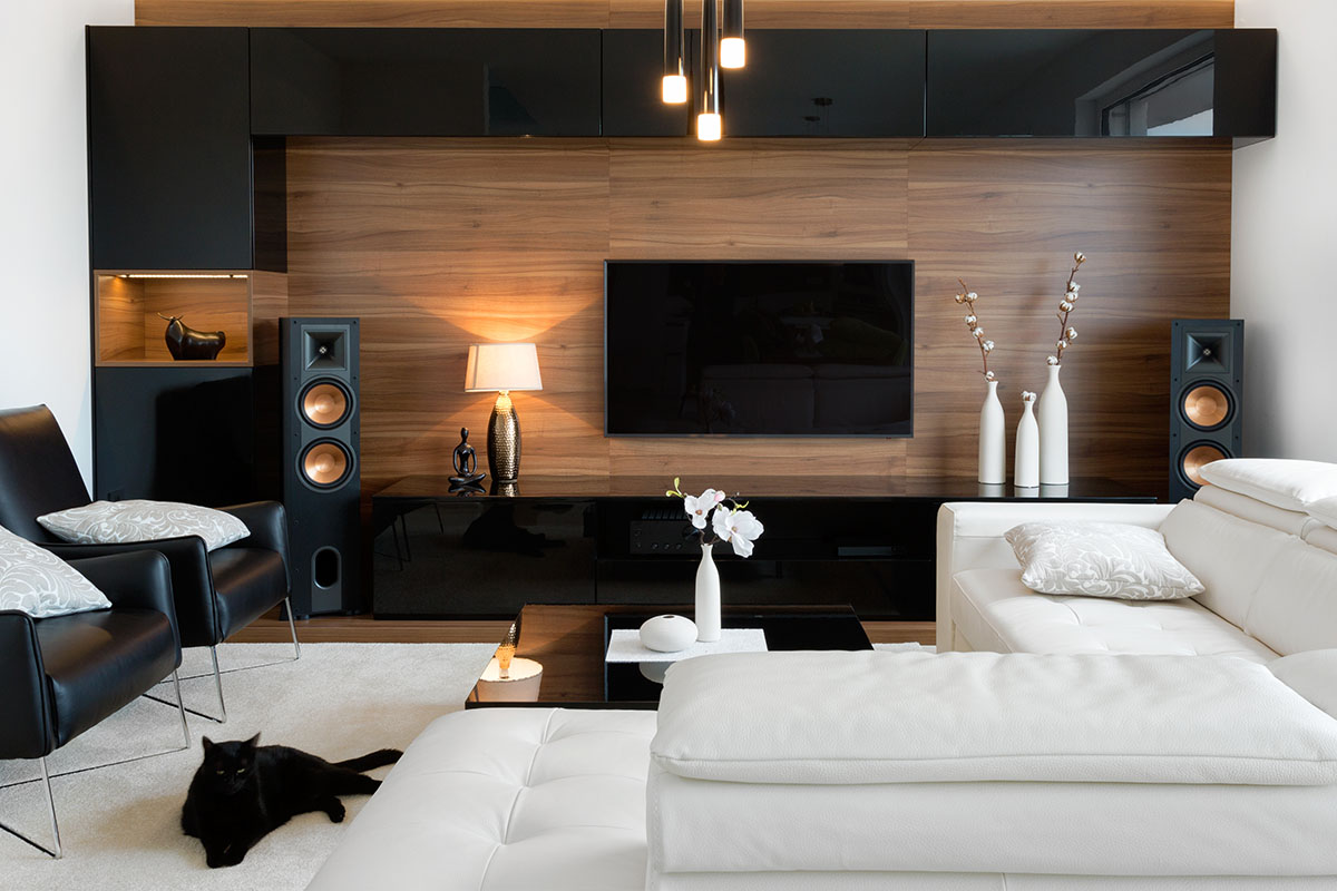 Wohnzimmer modern einrichten mit schwarzer TV-Wand und weißes Sofa.